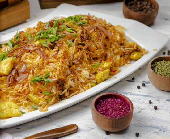 Chicken breast, tomato sauce rice, risotto, plov with herbs , yogurt and sumakh in white plate. image